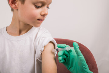 Boy getting flu shot. Cropped nurse giving child intramuscular antivirus injection. Vaccination for...