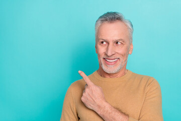 Portrait of satisfied aged man look direct finger empty space proposition isolated on turquoise color background