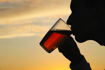 Young man drinking tea from a glass on a sunset background. Photo was taken 23 June 2022 year, MSK...