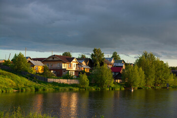 Naklejka na ściany i meble a village on the river bank with bright green grass and a beautiful sky.