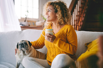Happy female dog owner smile and enjoy happy time at home with her best friend old pug sitting near...