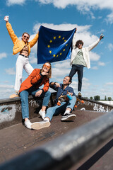 happy multicultural friends with european union flag in skate park.