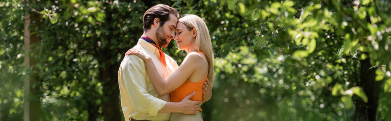 Side view of trendy romantic couple embracing in summer park, banner.