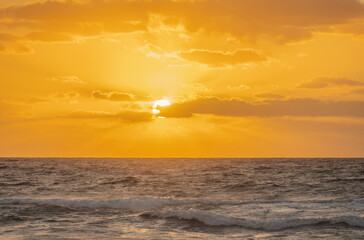 Golden sky with sun and calm ocean at sunset