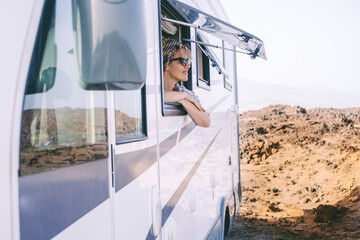 Summer holiday travel vacation with renting camper van motor home. Happy woman admiring outside the...