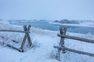 USA, Idaho, Bellevue, Wooden fence in snow covered field near river