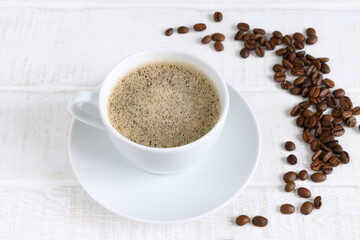 Cup of coffee and coffee beans on white wooden table Top view