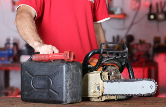 person with a chainsaw and a fuel canister on a table - Powered by Adobe