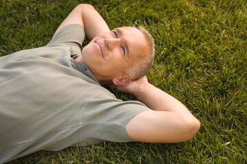 Mature man lying on grass and smiling