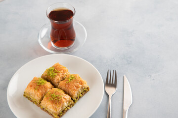 Baklava pistachio on a white plate with Turkish tea

