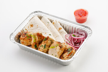Pita with chicken skewers and round onions and sauce in the tray on a white background