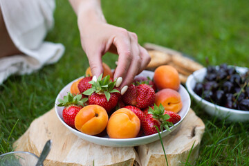 Women's hands hold a plate of strawberries on the street