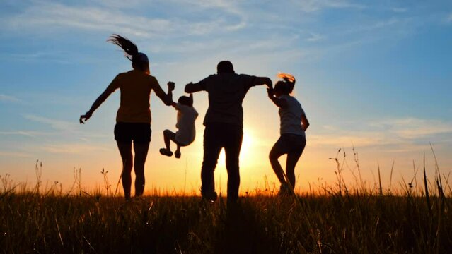 Silhouette happy family. Parents and little son fun at sunset. Silhouette family play at sunset. Teamwork child and parents fun in the park. Friendly family and kid dream concept.