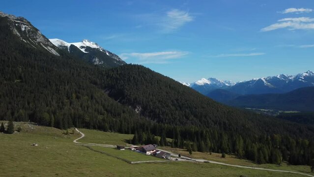 Cinematic aerial view from a drone flight over H&auml;mmermoosalm in the Gais Valley with snow covered peaks behind, located in Austria