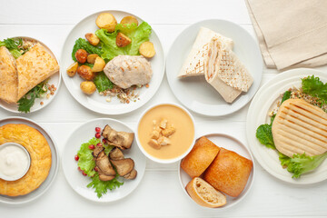 Set lunch - soup, chicken, potatoes, lettuce, cheese, roll, cakes, vegetables and casserole. Top view