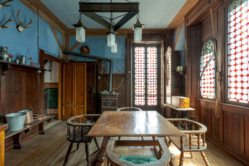 Dining room with wooden table and armchairs, wall with blue upholstery and deer antlers hanging on the wall