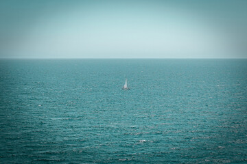 Sailing boat in a distance on open water. Mediterranean Sea with a blue sky