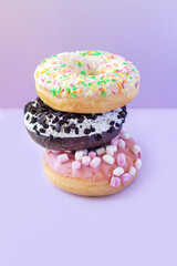 Stack of different sweet donuts with sprinkles on table
