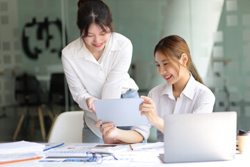 Fototapeta premium Businesswoman colleagues in the office discussing work and planning projects together on a tablet at their desk.