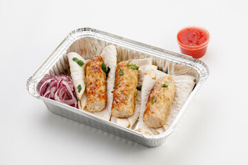 Pita with sausage on it with round onion, sauce, in the tray on a white background