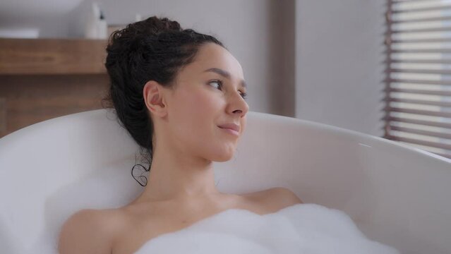 Close-up young attractive relaxed woman lying in hot foam bath with eyes closed resting relaxing in bathroom happy carefree pensive dreamy girl enjoying daily hygiene routine bathing washes bodycare