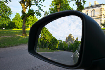 Side rearview mirror on a car. View of the church from the car.
