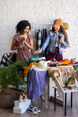 Obraz premium Young women at swap home party - clothes, shoes, bags, jewellery exchange between friends. Zero waste shopping, eco friendly concept, sustainable lifestyle. College life. 
