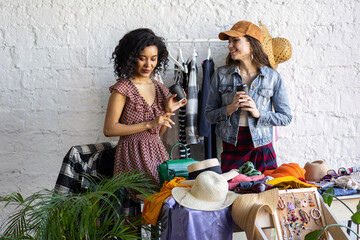 Young women at swap home party - clothes, shoes, bags, jewellery exchange between friends. Zero waste shopping, eco friendly concept, sustainable lifestyle. College life. 