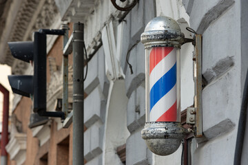 Chromed barber pole cylinder at the wall of an old wall in town