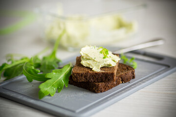 bread cheese spread with garlic and arugula on dark bread