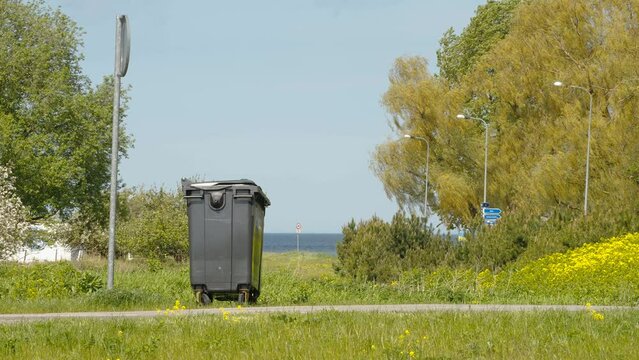 The landscape view of the park in Estonia with the garbage bin and the signage pole
