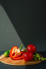 branches of fresh green asparagus, peppers, tomatoes and cucumbers on a wooden board, dark gray background, top view. Basic trend concept with copy space.