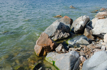 Stones on the shore of Lake Baikal in sunny summer weather.