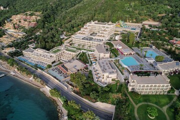 Aerial drone view of beautiful beach front hotel resort with swimming pool, umbrellas and turquoise sea. Paradise destination, Corfu, Greece. 