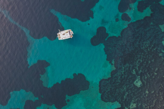 Aerial drone top down photo of luxury yacht anchored in tropical exotic island bay with crystal clear turquoise sea