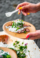 woman hand holding paper plate with meat and sause outdoor