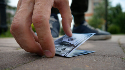 A man found one hundred dollar bill on the sidewalk and he bent down to pick it up