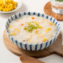 Delicious rice porridge congee with corn kernel and vegetables on white table background.