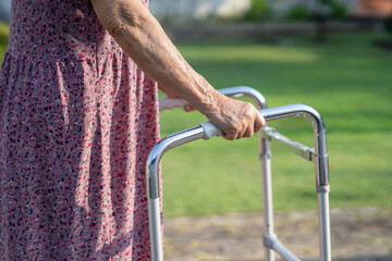 Asian senior or elderly old lady woman use walker with strong health while walking at park in happy fresh holiday.