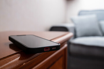 Smartphone is inadvertently left on the edge of a wooden table and may fall. Concept of careless attitude to things. 