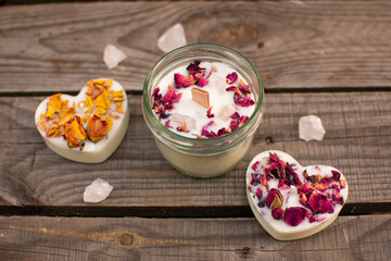 Kerze mit Rosenblütenblättern und Halbedelsteinen aus Rosenquarz Im Schraubglas und zwei Kerzen in Herzform. Ansicht von oben