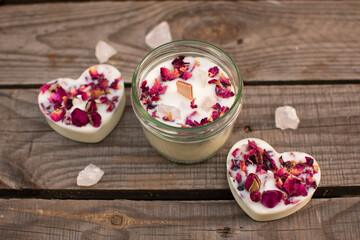 Kerzenset: Duftkerze im Glas mit Holzdocht, Rosenblütenblättern und Halbedelsteinen aus Rosenquarz Im Schraubglas dazu zwei Kerzen in Herzform. Ansicht von oben