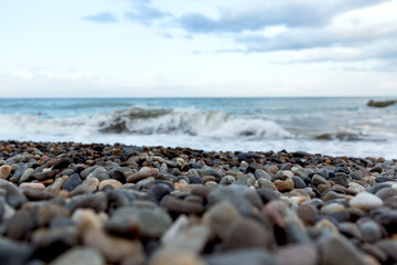 Seascape. Blue and gray pebbles on the beach. White sea waves. Skyline. Nature multicolored background.