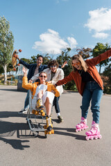 happy skater waving hand in shopping trolley near excited friends.