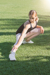 The girl stretches her muscles before running.