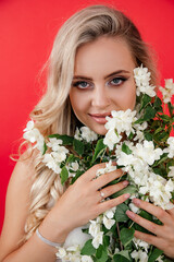 Sensual Portrait of young beautiful woman with jasmine flowers on red background. Pure skin, concept, natural cosmetics
