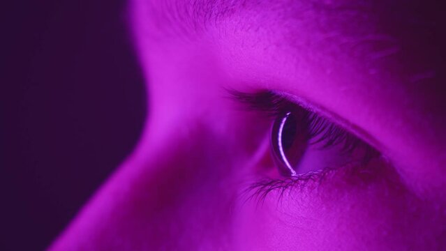 Young girl blinking eye closeup loop. Purple lighting. Profile. Slow motion. Macro. 
