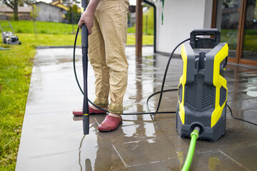 High water pressure cleaner on wet concrete terrace surface. 