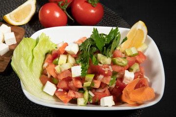 Caprese Salad.Mediterranean Salad. Mozzarella with cherry tomatoes basil and olive oil on black table. Italian cuisine.