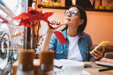 Portrait of brunette girl wearing eyeglasses studying in cafe
